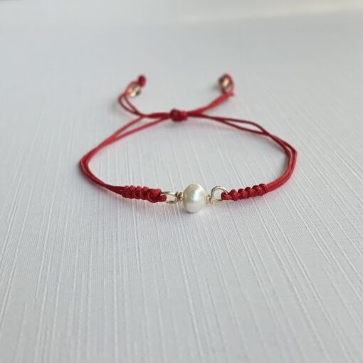 Pulsera Protección con perla natural, cordón rojo ajustable y detalles en goldfilled
